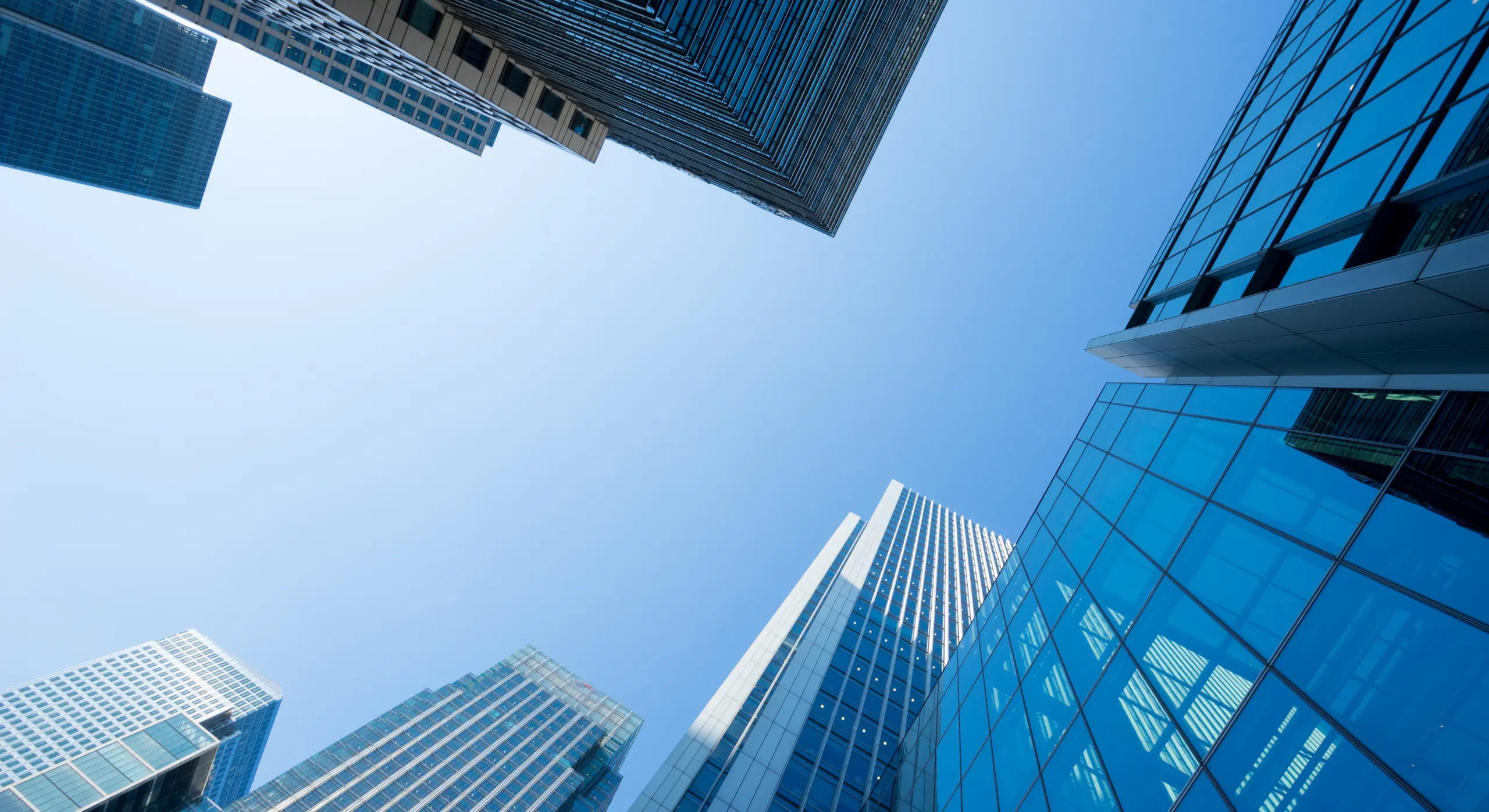 Glass office tower buildings viewed from below against blue sky