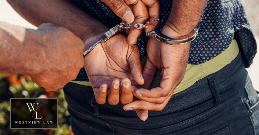 Criminal Penalties for Wage Theft Under AB 1003 Close-up of a worker's hands being cuffed behind their back, illustrating the criminal charges an employer can face for wage theft in California