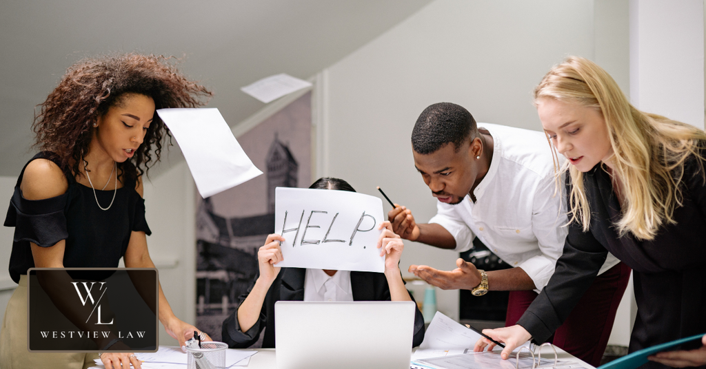 Overwhelmed employee surrounded by coworkers, representing intimidation and retaliatory treatment in the workplace.