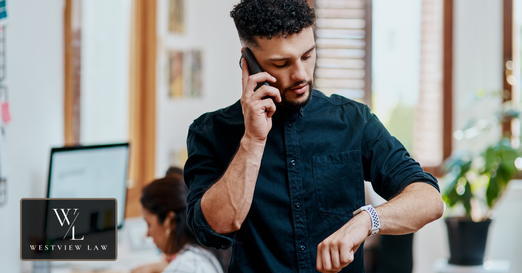 Employee checking the time while making a phone call at work, representing timing and documentation in a retaliation claim.