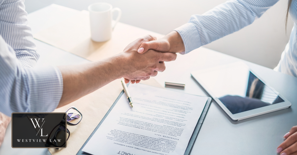 Employer and employee shaking hands over a contract representing employment promises and agreements.