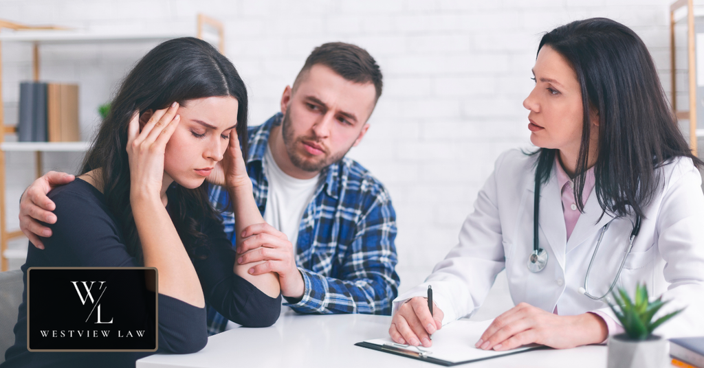 Distressed woman speaking with a medical professional while receiving support from her partner.