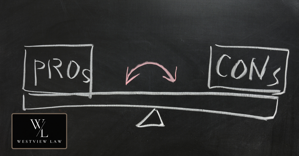 Balance scale drawn on a chalkboard comparing the pros and cons of pursuing legal action against an employer.